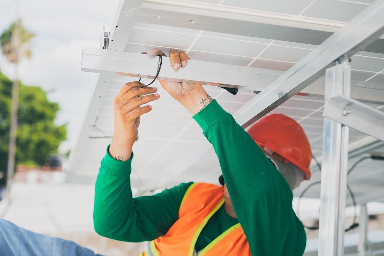 about-img A solar technician in PPE installs a solar panel, showcasing renewable energy work.