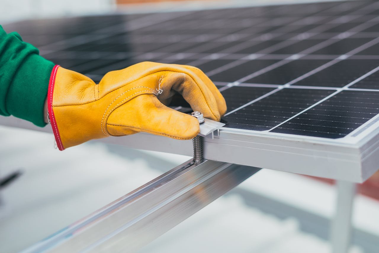 hero-gallery-03 Close-up of a workers hand with protective gloves adjusting a bolt on a solar panel.