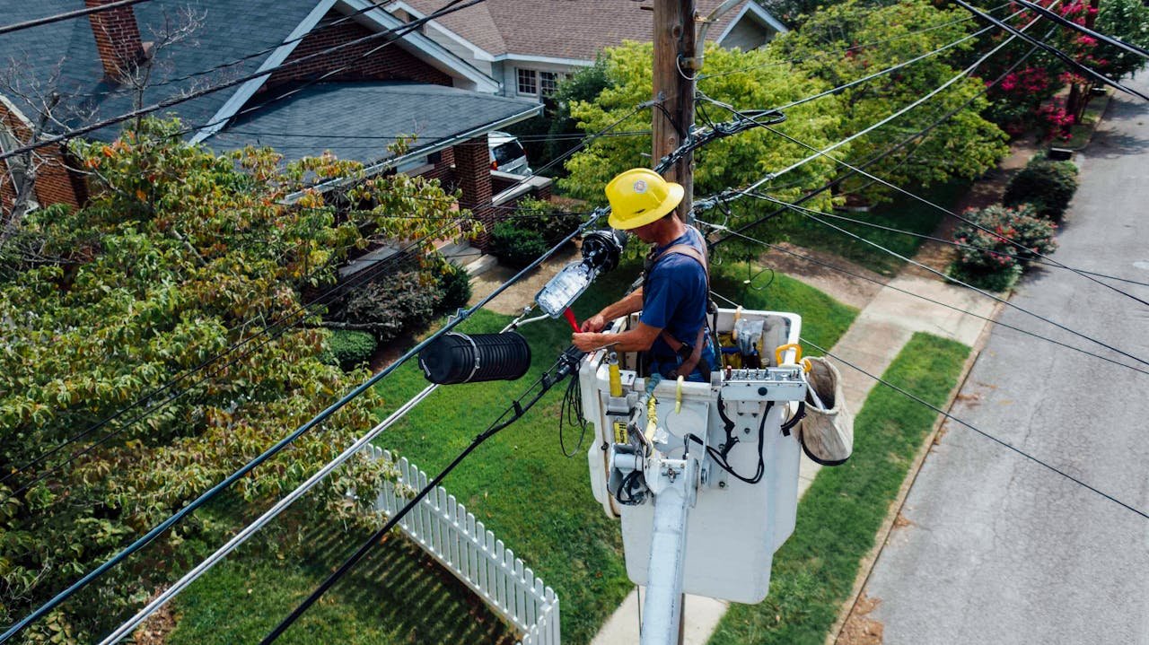 hero-gallery-01 Electrician in a bucket lift repairing power lines from a utility pole in a suburban neighborhood.